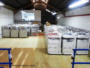 Optimus Copier's Warehouse filled with multiple wrapped photocopier machines available for copier rental, featuring organized rows of copiers ready for immediate rental or lease.